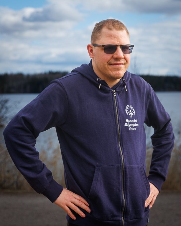 Timo Averjanov poseeraamassa kameralle aurinkolasit ja sininen SO-huppari päällään.